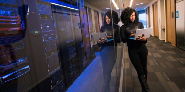Picture of woman with computer beside a large bank of computer stacks